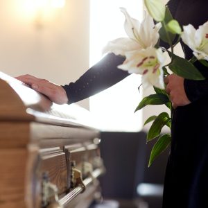 woman-with-lily-flowers-and-coffin-at-funeral.jpg